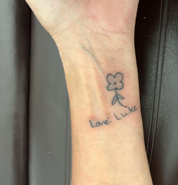 Fiorellino e scritta tattoo sul polso